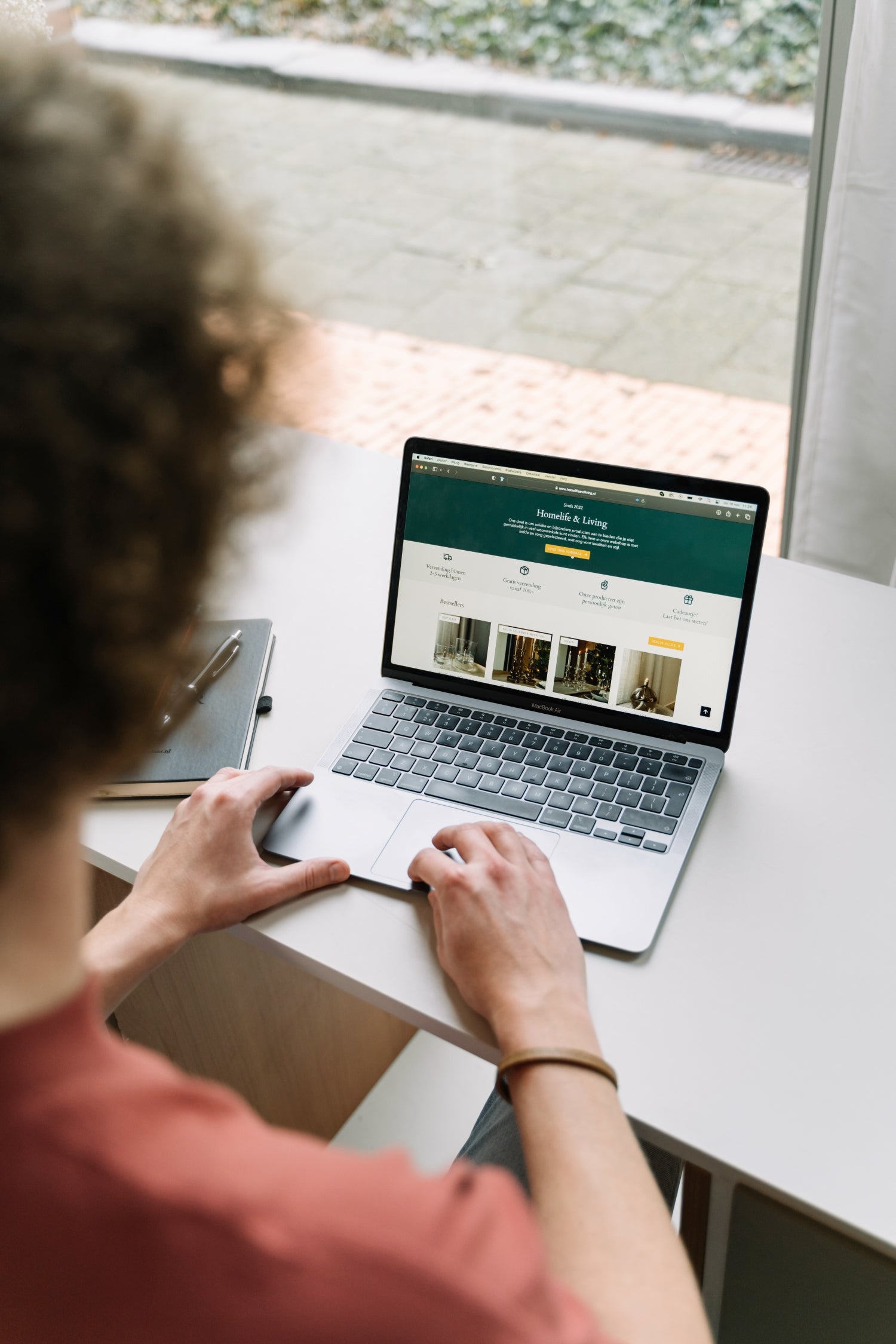 De WBshopmaker kijkend naar zijn MacBook met daarop een webshop.