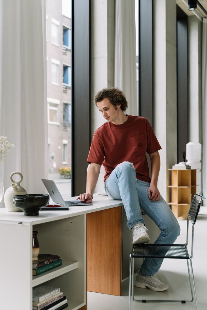 De WBshopmaker leunend op een bureau werkende aan een webshop