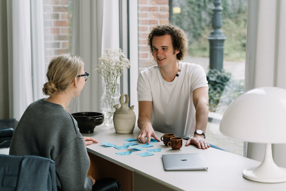 De WBshopmaker wijzend naar blauwe post-its en kijkend naar klant