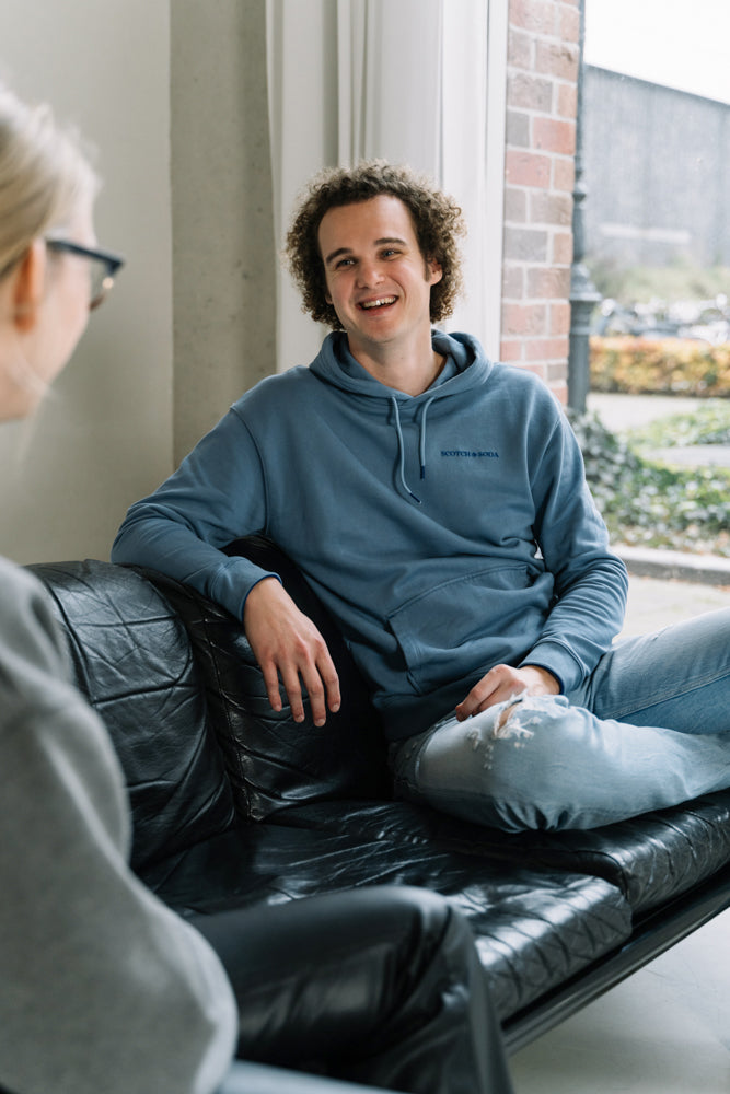 De WBshopmaker lachend naar zijn klant op een zwart bureau